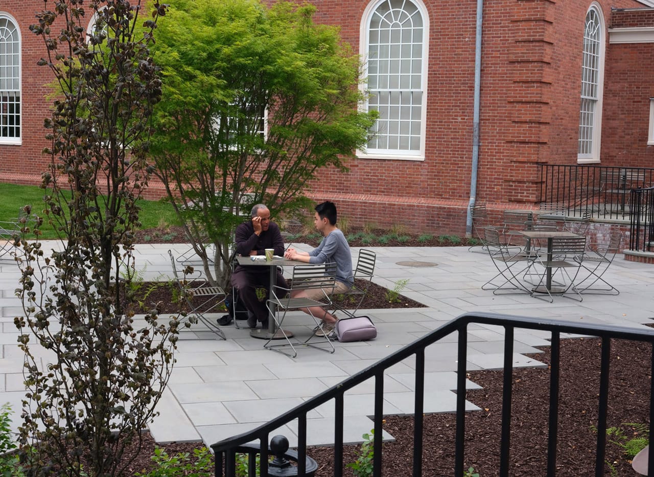 Two men talking at an outdoor table on the YDS campus